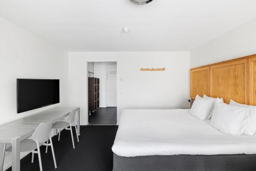 a bedroom with a bed and a table and a tv at B's Strandappartementen in Domburg