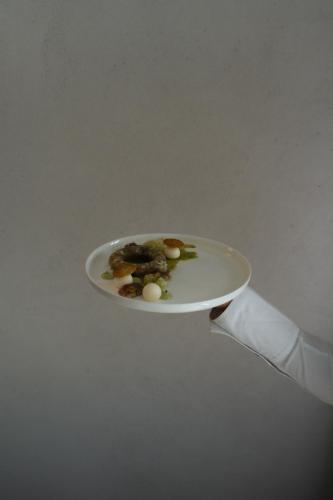 a person holding a plate with a spatula holding a knife at Hotel Haus am See in Nonnenhorn