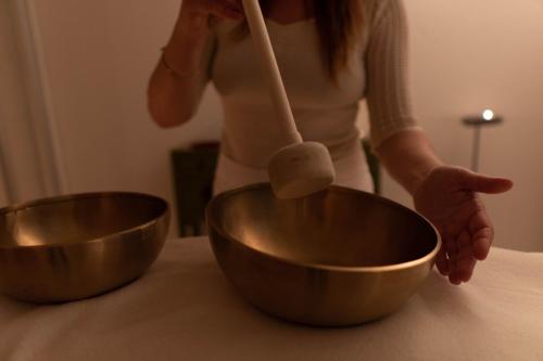 a woman is mixing two copper bowls on a counter at Hotel Haus am See in Nonnenhorn
