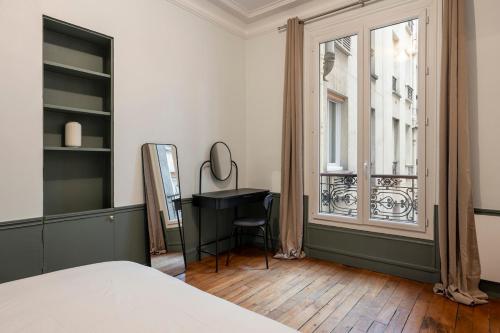 une chambre avec un lit, un bureau et une fenêtre dans l'établissement Appartement Élégant et Spacieux dans le 8ème, à Paris