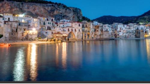 a group of white buildings on the water at night at Holiday Homes in Campofelice di Roccella