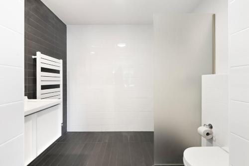 a white bathroom with a toilet and a sink at B's Strandappartementen in Domburg