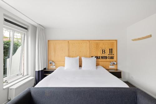 a bedroom with a large white bed and a window at B's Strandappartementen in Domburg