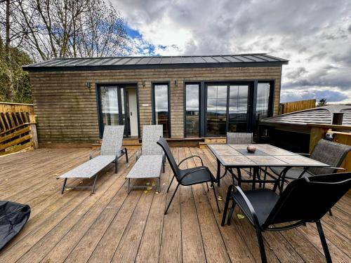 a deck with a table and chairs and a building at Burtree Country House, Tipi's, Treehouse & Lodge & house rooms with hot tubs in a private garden in Thirsk
