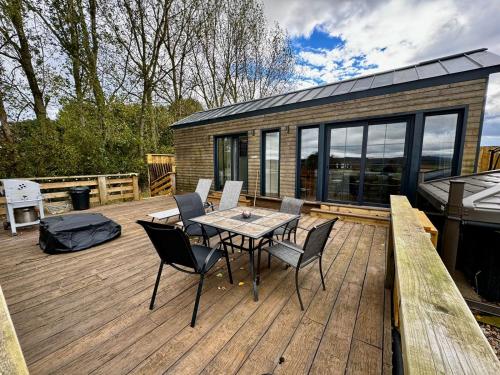 a wooden deck with a table and chairs on it at Burtree Country House, Tipi's, Treehouse & Lodge & house rooms with hot tubs in a private garden in Thirsk