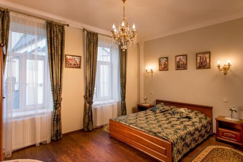 a bedroom with a bed and two windows and a chandelier at Lviv hollidays Galytska in Lviv