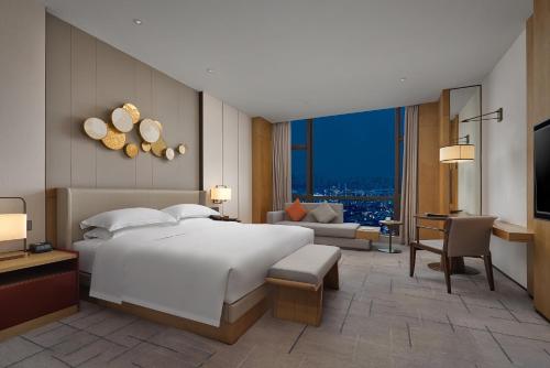 a bedroom with a large white bed and a living room at Dongguan DongCheng International Hotel - Free shuttle buses for executive room guests during Canton Fair in Dongguan