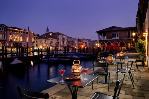 a table with wine glasses and chairs next to a canal at L'O Venezia Flat - WTB Hotels in Venice