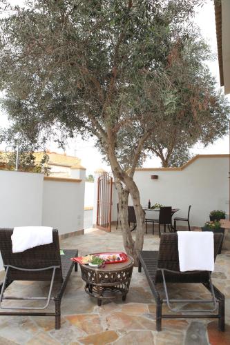 a tree on a patio with chairs and a table at Bono Vacanze Villa San Marco Luxury Holidays Homes in Sciacca