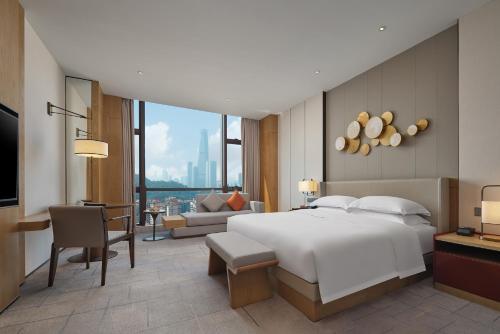 a bedroom with a large white bed and a living room at Dongguan DongCheng International Hotel - Free shuttle buses for executive room guests during Canton Fair in Dongguan