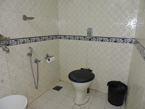 a bathroom with a toilet with a black seat at Zappia Cove Resort Palolem in Palolem