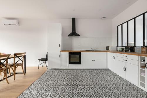une cuisine avec des armoires blanches et une table et des chaises dans l'établissement T3 Spacieux et Moderne - Climatisation, Parking & Terrasse, à Pibrac