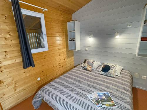 ein Schlafzimmer mit einem Bett in einem Holzzimmer in der Unterkunft Village de Chalets in Joyeuse