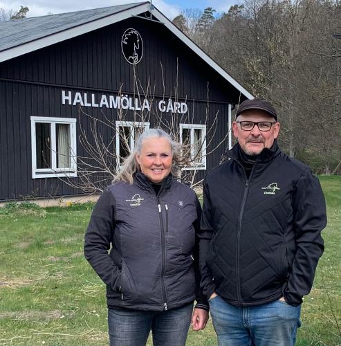 a man and woman standing in front of a black barn at Hallamölla Gård in Brösarp