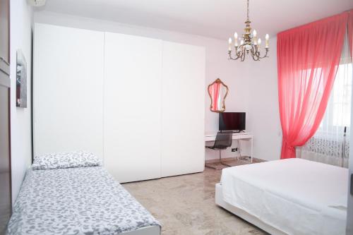 a white bedroom with two beds and a chandelier at Villa Fiorita in Mediglia