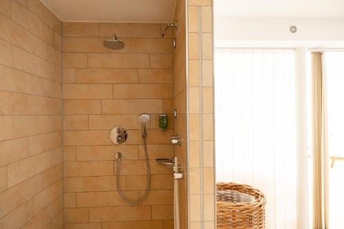 a shower with a shower head in a bathroom at Hotel Haus am See in Nonnenhorn