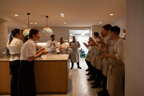 a group of people standing around a counter in a kitchen at Hotel Haus am See in Nonnenhorn
