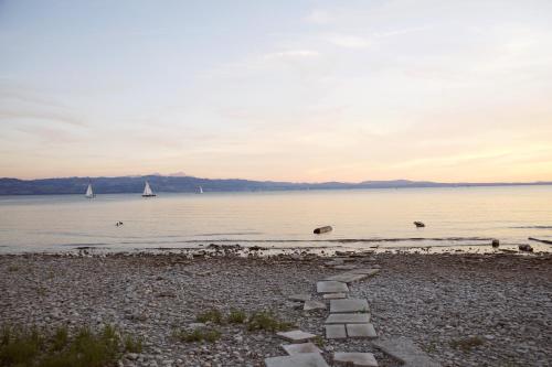 a path on the shore of a lake with a sail boat at Hotel Haus am See in Nonnenhorn