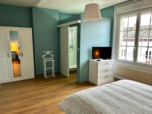- une chambre avec des murs bleus, un lit et une télévision dans l'établissement Le Grand' Appart, à Jonchery-sur-Vesle