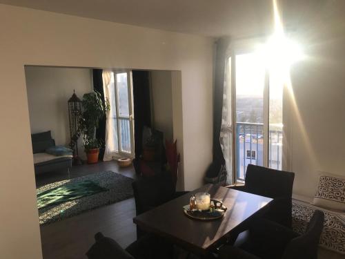 un salon avec une table et une grande fenêtre dans l'établissement Nice place 80m2- 2 to 8 beds- 30min from Paris 15min Aeroport Orly, à Créteil
