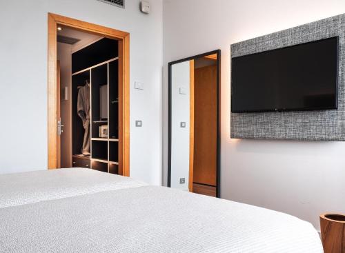 a bedroom with a bed and a flat screen tv on a wall at INNSiDE by Meliá Barcelona Aeropuerto in El Prat de Llobregat