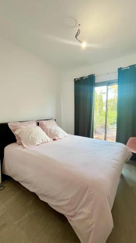 une chambre avec un grand lit blanc avec une fenêtre dans l'établissement Appartement avec jardin proche de la mer, à Agay