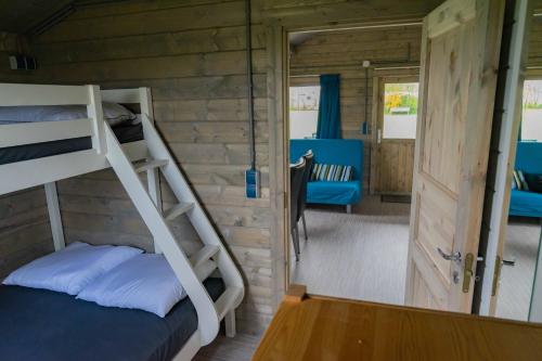 a bunk bed in a cabin with a door and a room at Camping Sudersé in Workum