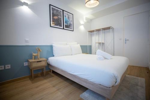 - une chambre avec un grand lit blanc et une table de nuit dans l'établissement Sd Appartement familiale au coeur de la rue Saint Denis, à Paris