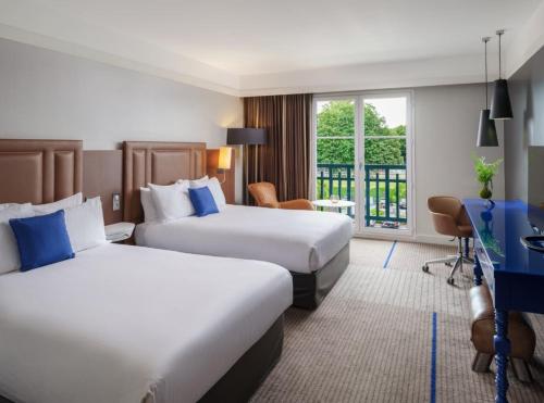 a hotel room with two beds and a desk at Renaissance Paris Hippodrome de St. Cloud Hotel in Rueil-Malmaison