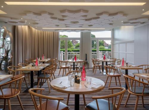 a restaurant with tables and chairs in a room at Renaissance Paris Hippodrome de St. Cloud Hotel in Rueil-Malmaison