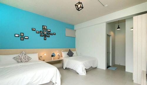 a bedroom with two beds and a blue wall at Happiness 210 B&B in Dongshan