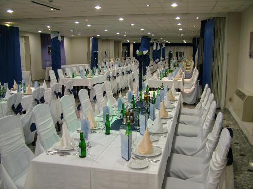 a banquet hall with white tables and white chairs at Hotel Silver in Hajdúszoboszló