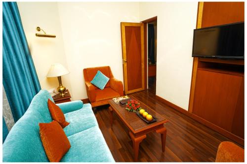 a living room with a blue couch and a table at Ambassador Ajanta Hotel, Aurangabad in Aurangabad