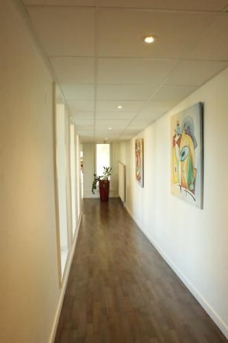 an empty hallway in an office building with paintings on the walls at Hotel Val Vert in Pouilly-en-Auxois