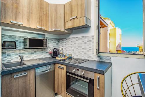 une cuisine avec un évier et une cuisinière four supérieur dans l'établissement DOUMER - Cosy deux pièces - Frontière Monaco, à Beausoleil