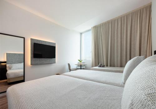 a hotel room with two beds and a flat screen tv at INNSiDE by Meliá Barcelona Aeropuerto in El Prat de Llobregat