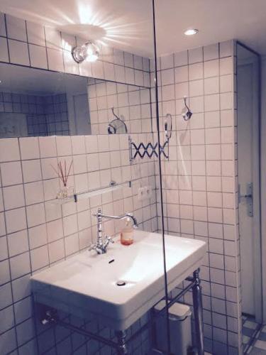 La salle de bains est pourvue de carrelage blanc, d'un lavabo et d'un miroir. dans l'établissement Dupleix 75m2 sur cour arborée, à Paris