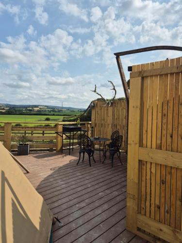 a wooden deck with a table and chairs on it at Burtree Country House, Tipi's, Treehouse & Lodge & house rooms with hot tubs in a private garden in Thirsk