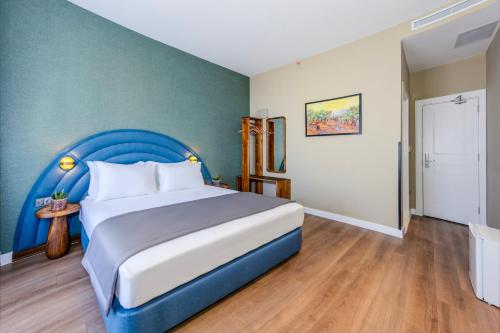 a bedroom with a large bed with a blue headboard at Nenessa Airport Hotel in Arnavutköy