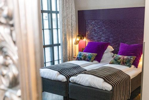 a bedroom with a bed with purple pillows at Hotel Oleana in Bergen