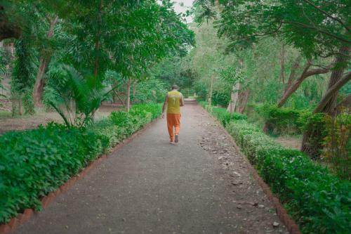 a man walking down a path in a park at Ambassador Ajanta Hotel, Aurangabad in Aurangabad