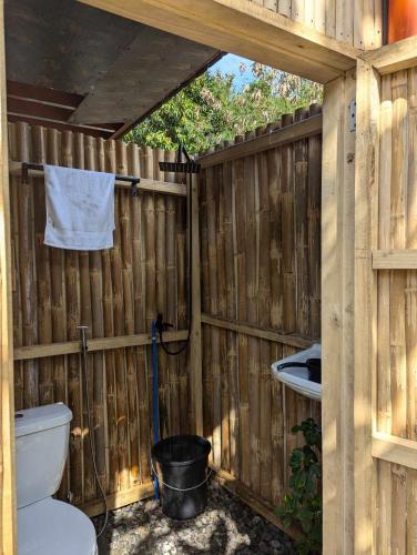 a bathroom with a toilet and a wooden fence at Glowbu Kabins in San Juan