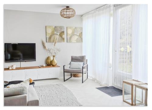 a white living room with a tv and a chair at Cozy Holiday Home with Private Garden at Waterpark in Grou in Grou