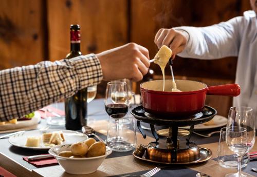 a person cooking food in a pot on a table at Monte Rosa Boutique Hotel in Zermatt