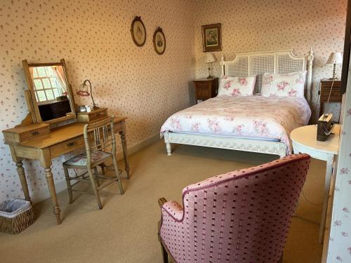 a bedroom with a bed and a desk with a television at Peacocks Tearoom and Fine B&B in Ely