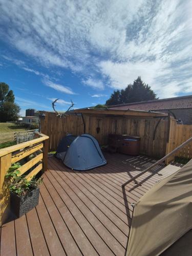 a blue tent on a deck with a fence at Burtree Country House, Tipi's, Treehouse & Lodge & house rooms with hot tubs in a private garden in Thirsk