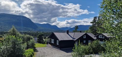 een zwart huis met bergen op de achtergrond bij Panorama Cabin - Stunning Mountain Views and Outdoor Jacuzzi Option in Bjorli
