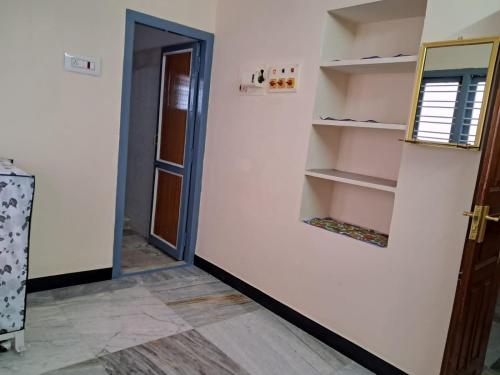a hallway with a door and a room with shelves at Room 3 in Orange Homestay in Thanjāvūr