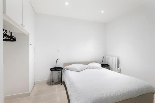 - une chambre blanche avec un lit et deux tables dans l'établissement Au Maire - Appartement familiale, à Paris