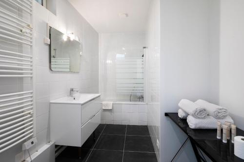 La salle de bains blanche est pourvue d'un lavabo et d'une baignoire. dans l'établissement Au Maire - Appartement familiale, à Paris